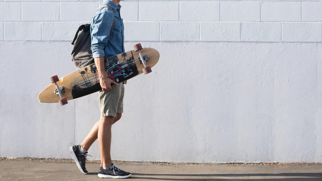 Man In Blue Top Carrying A Longboard